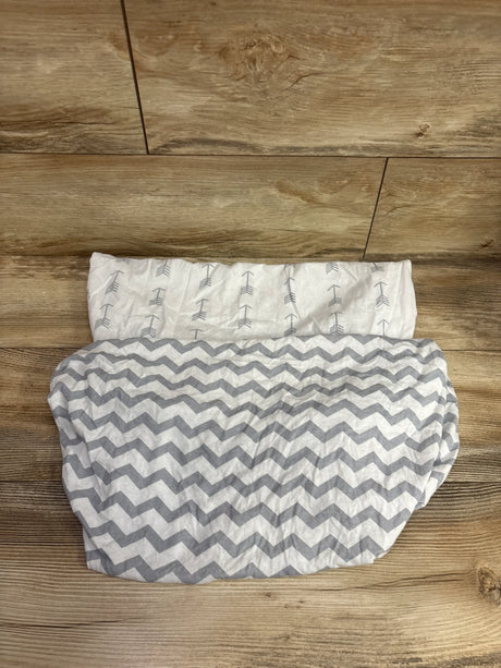 Top view of 2-pack fitted bassinet sheets showing gray chevron and arrow patterns on white fabric against a wood floor