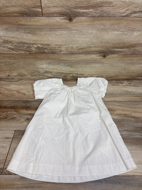 Top-down view of Zara ivory short sleeve dress with gathered sleeves and flared skirt on a wood floor