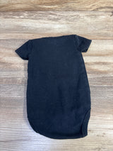 Back view of newborn black bodysuit showing short sleeves and plain knit fabric on a wood background