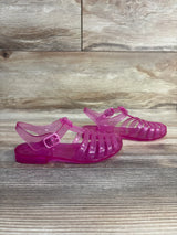 Side view of Janie and Jack Jelly Fisherman Sandals in translucent pink showcasing caged upper and buckle ankle strap on wood plank floor