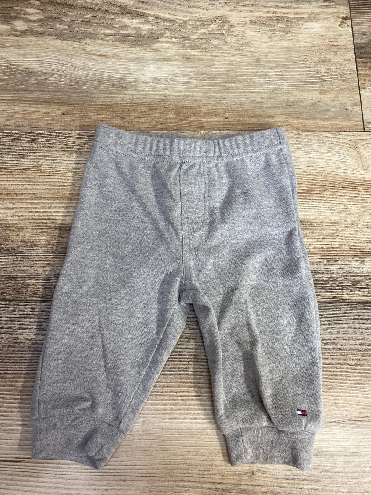Gray toddler sweatpants with elastic waistband and small logo on leg, on wood floor
