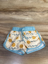 Front view of Caden Lane Sunshine swim trunks with cream background, smiling sun and blue wave print, blue trim on wood floor