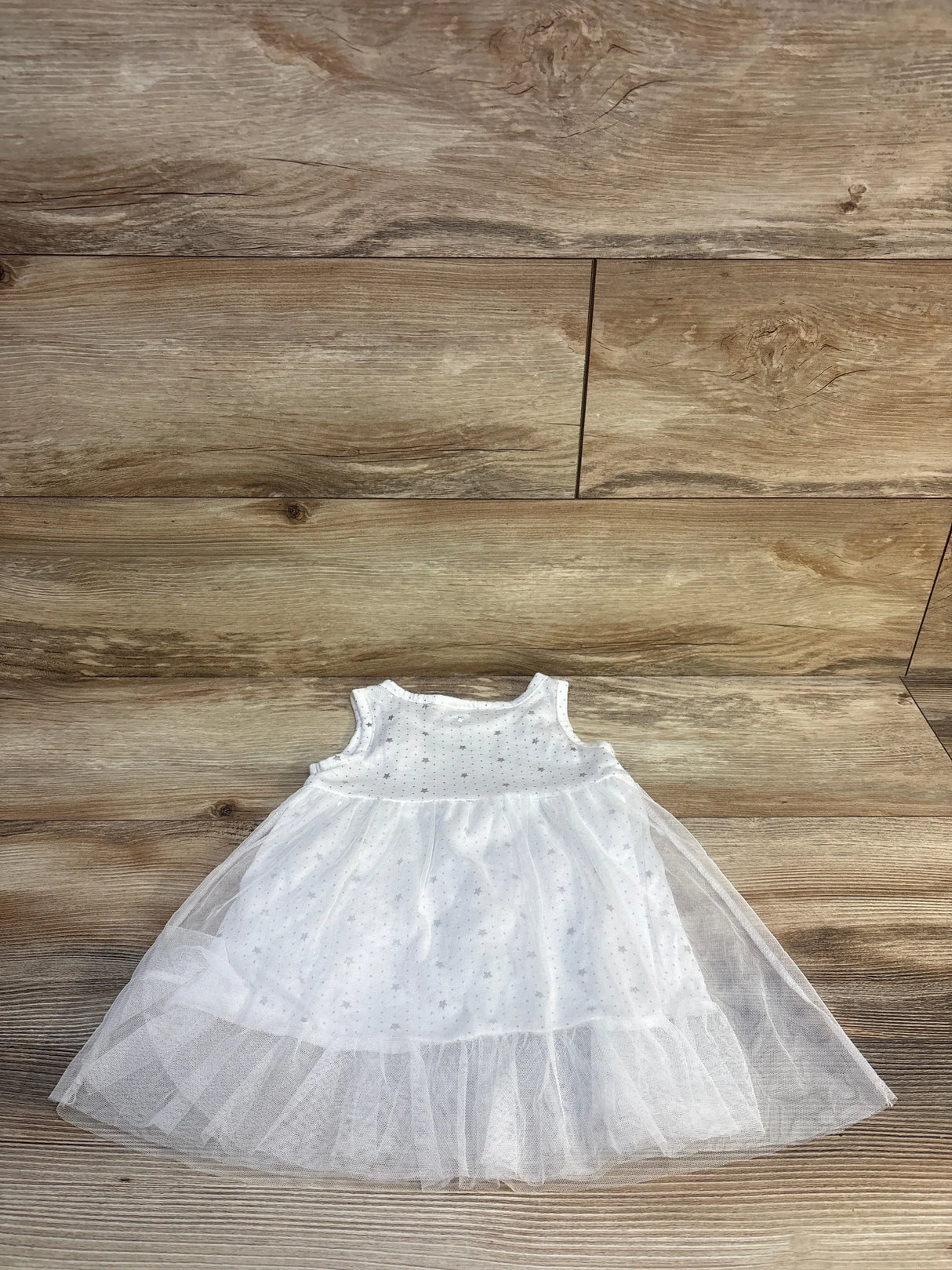 White sleeveless toddler dress with tulle skirt and star pattern on wooden floor