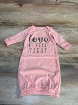Pink baby gown with 'love at first sight' text, long sleeves, laid flat on wood floor