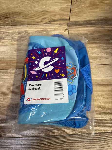 Front view of Paw Patrol kids backpack in clear packaging, blue color with front logo patch and mesh side pocket on wood tabletop