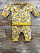Yellow baby outfit with cartoon animal faces and rainbows, long sleeves, on wood floor