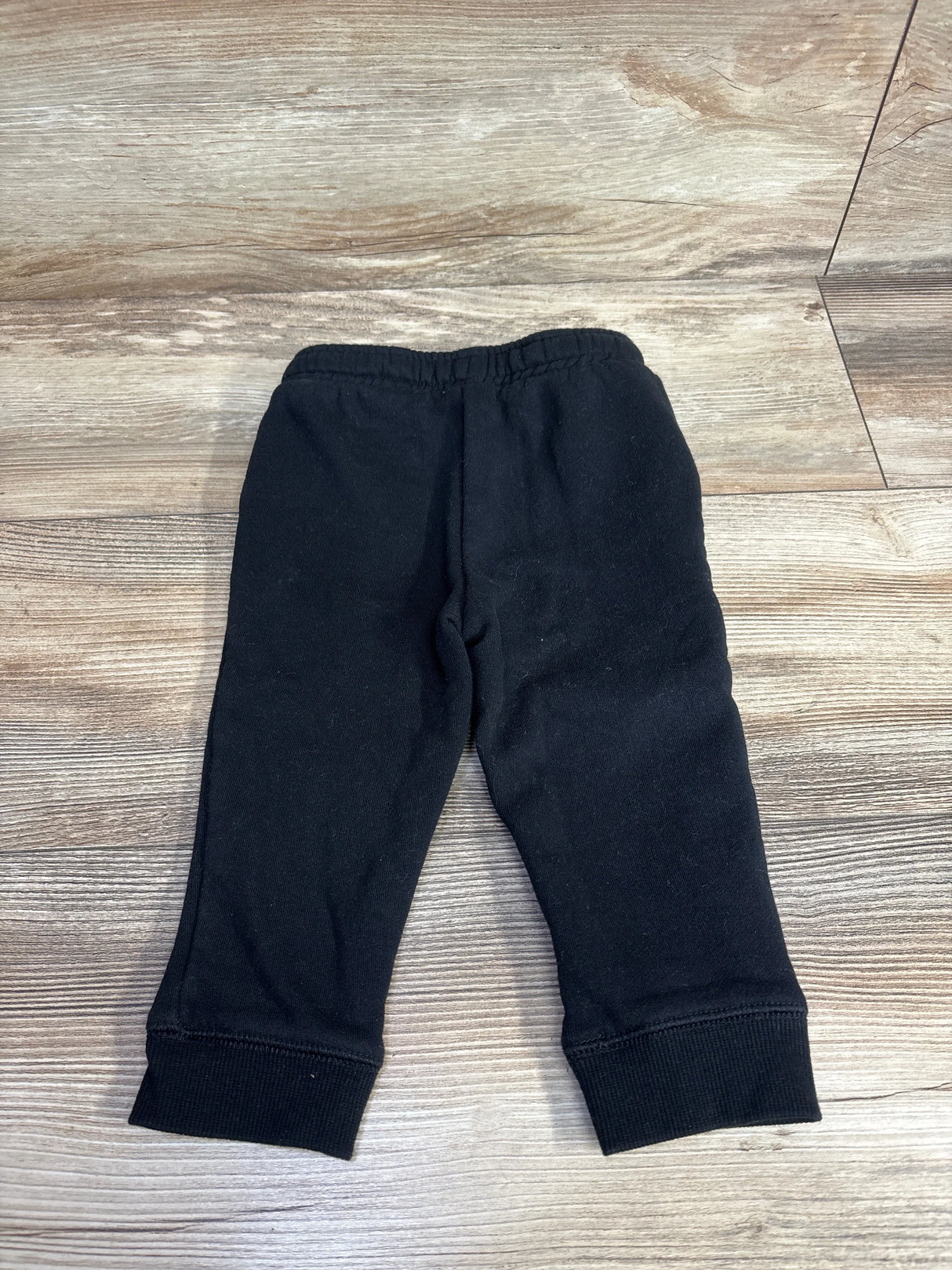 Black toddler pants with elastic waistband on wood surface
