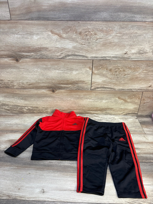 Kids Adidas red and black tracksuit set with jacket and pants on wood background