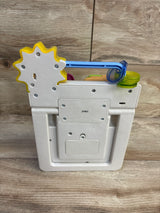 Rear view of Fisher-Price Peek & Play Busy Garden toy showing battery compartment and yellow gear with wood background