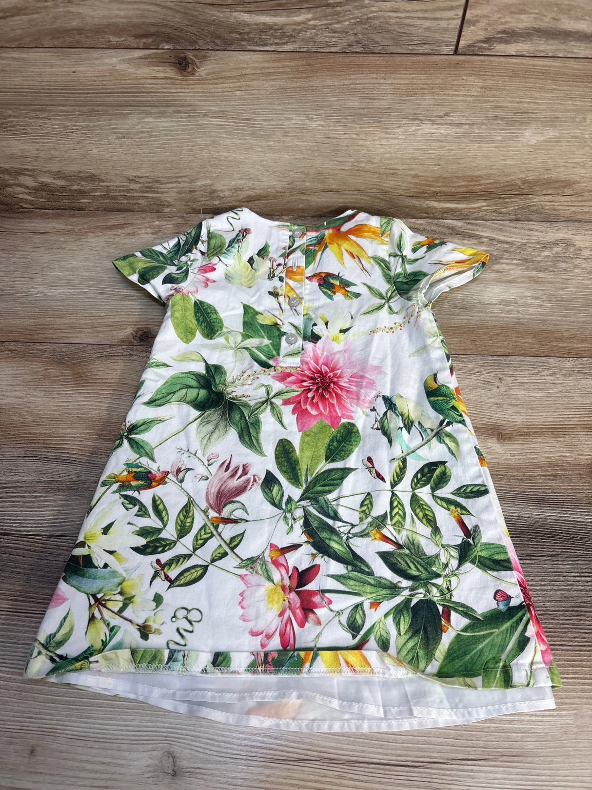Floral short sleeve toddler dress with colorful flowers on a wooden floor