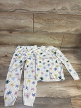 Flat lay of Hanna Andersson 2pc organic long johns pajama set in ivory, size 5T, with colorful starburst print on wood floor
