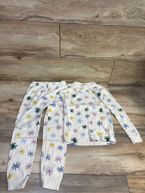 Flat lay of Hanna Andersson 2pc organic long johns pajama set in ivory, size 5T, with colorful starburst print on wood floor