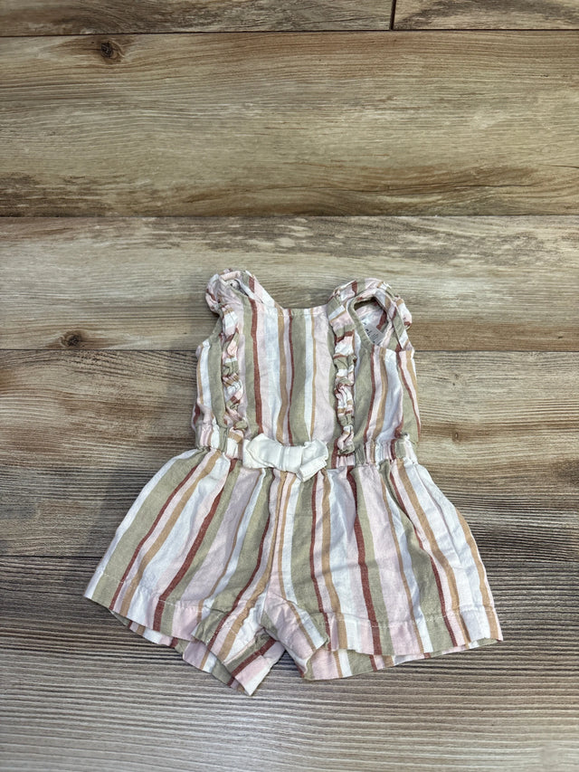 Top-down view of white linen striped baby romper with ruffled shoulder straps, elastic waist and small front bow on wood background