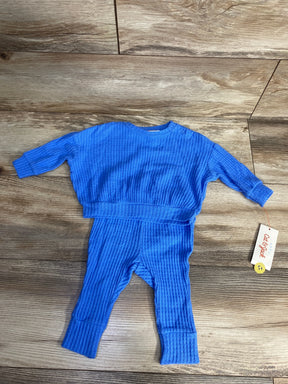 Blue textured baby outfit with long sleeves and pants laid on wooden floor, Cat & Jack brand tag