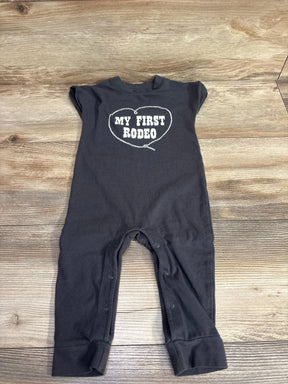 Flat lay of Cat and Jack My First Rodeo Romper in dark gray sz 6-9m showcasing white heart-shaped graphic and snap leg closure on wood plank background