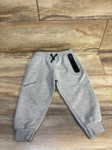 Gray kids joggers with 'Keeping It Authentic' text, black drawstring, and zip pocket on wood floor