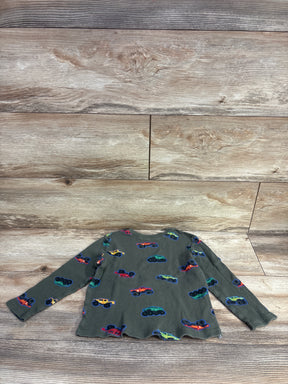 Olive green long-sleeve toddler shirt with colorful monster truck prints on wood background