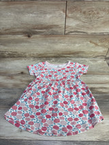 Flat lay of toddler floral dress by Touched By Nature showing pink rose print and gathered waist on wood plank background