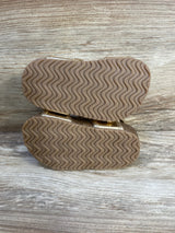 Bottom view of Just One You first-walker toddler sandals showcasing wavy rubber tread soles on wooden background
