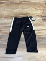 Front view of black Nike toddler joggers with white side panels, elastic waistband, and swoosh on wood background