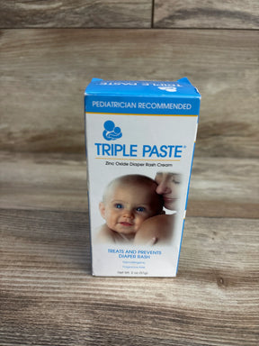 Front view of Triple Paste 2 oz zinc oxide diaper rash cream box showing branding and baby photo on wooden tabletop