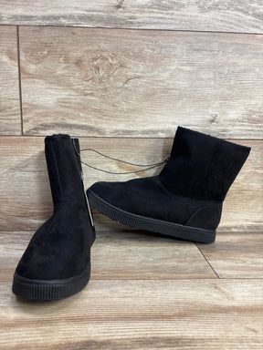 Black suede kids boots with rubber soles on wooden floor background