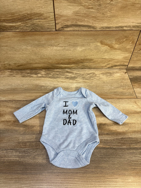 Top-down view of newborn blue long-sleeve baby bodysuit showing I heart MOM and DAD print and snap crotch on wood floor