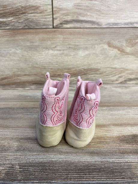 Front view of pink Stepping Stones cowgirl crib boots showing embroidered shaft, tan toe, and pull tabs on wood background