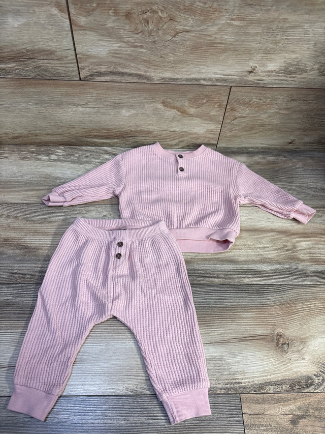 Top view of a pink 2 piece knit henley sweater and pants set with ribbed texture on a wood floor