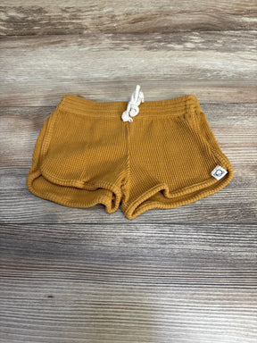 Flat-lay front view of My Little Cozmo organic waffle-knit baby shorts in oil yellow showcasing drawstring waistband on wood background