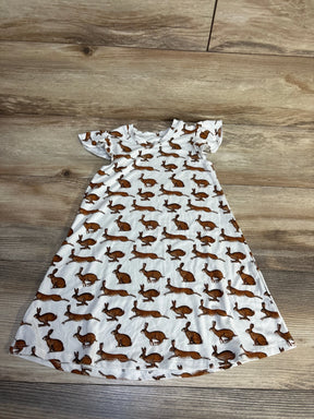 White short sleeve children's dress with brown bunny print, laid flat on wood surface