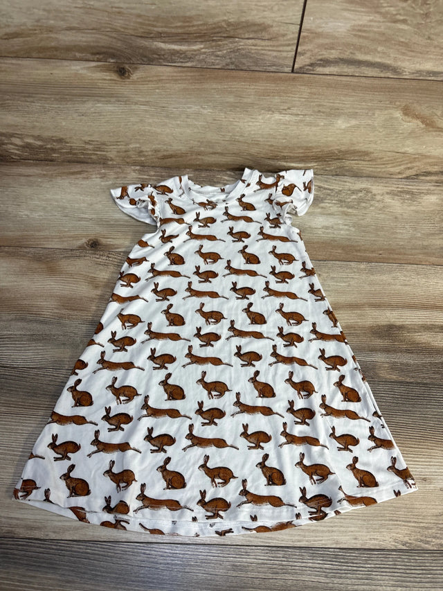 White short sleeve children's dress with brown bunny print, laid flat on wood surface