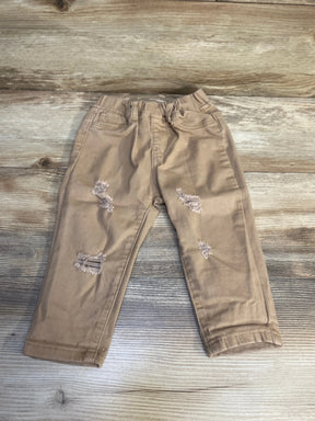 Tan distressed toddler jeans with front pockets on wood background