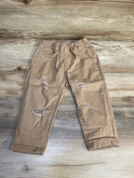 Tan distressed toddler jeans with front pockets on wood background