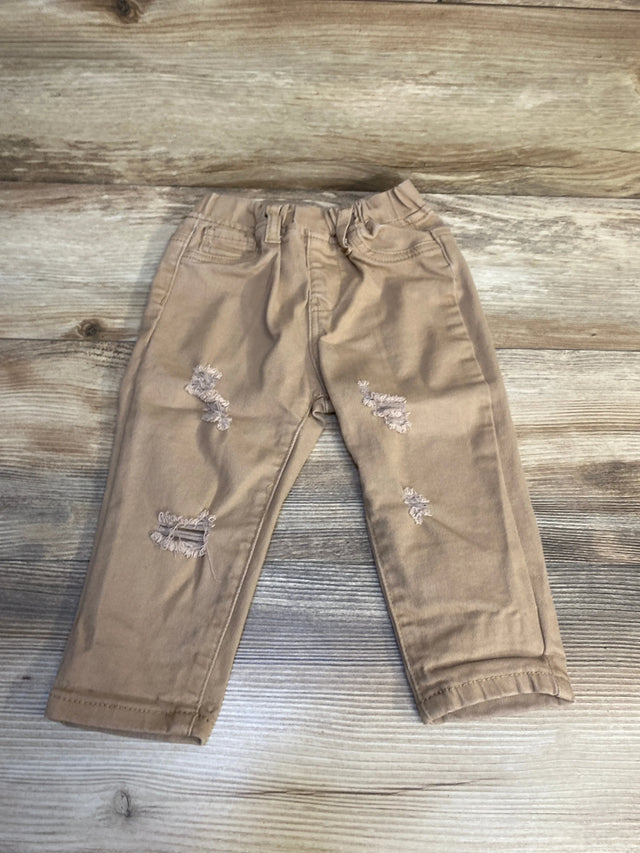 Tan distressed toddler jeans with front pockets on wood background