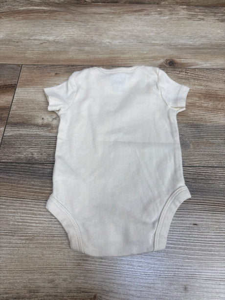 Overhead view of Carter’s cream newborn bodysuit showcasing short sleeves and leg openings on a wood grain background