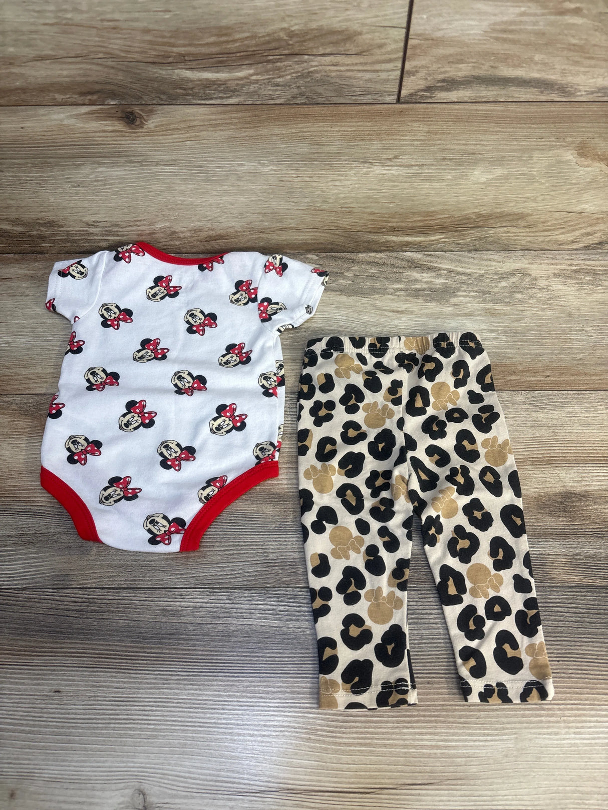 Baby girl outfit with Minnie Mouse print bodysuit and leopard print leggings on wood floor