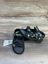 Front three-quarter of Rugged Bear kids' black sandals with green lightning print and Velcro straps on wood background