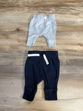 Flat lay of Carter's 2-pack preemie pull-on pants, light blue ribbed and navy pair with white drawstrings on wood surface
