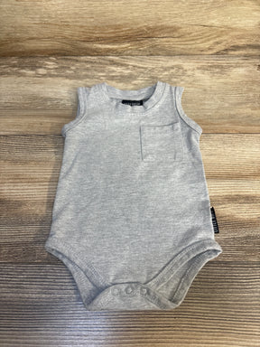 Gray sleeveless baby bodysuit with front pocket and snap closure, laid on wooden surface