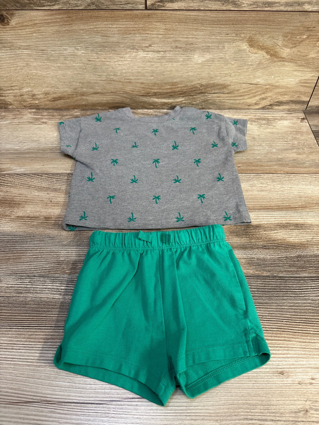 Flat lay of 2-piece baby set showcasing grey shirt with green palm tree print and green elastic shorts on wood background