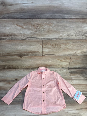 Light pink long sleeve kids button-up shirt with tag on wood background