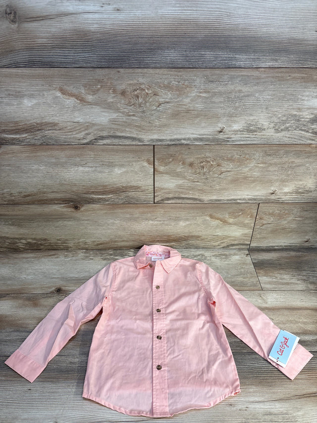 Light pink long sleeve kids button-up shirt with tag on wood background