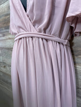 Close-up of blush Baltic Born maternity maxi dress showing gathered waist and fabric-covered belt with wood background