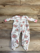 Flat lay of Magic Years floral snap sleeper showing all over pink rose print, pink cuffs and footed legs on wood background