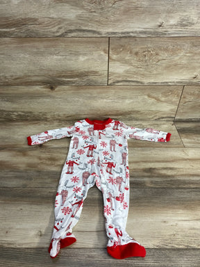 White baby footed pajamas with red reindeer and snowflake print, laid on wood floor