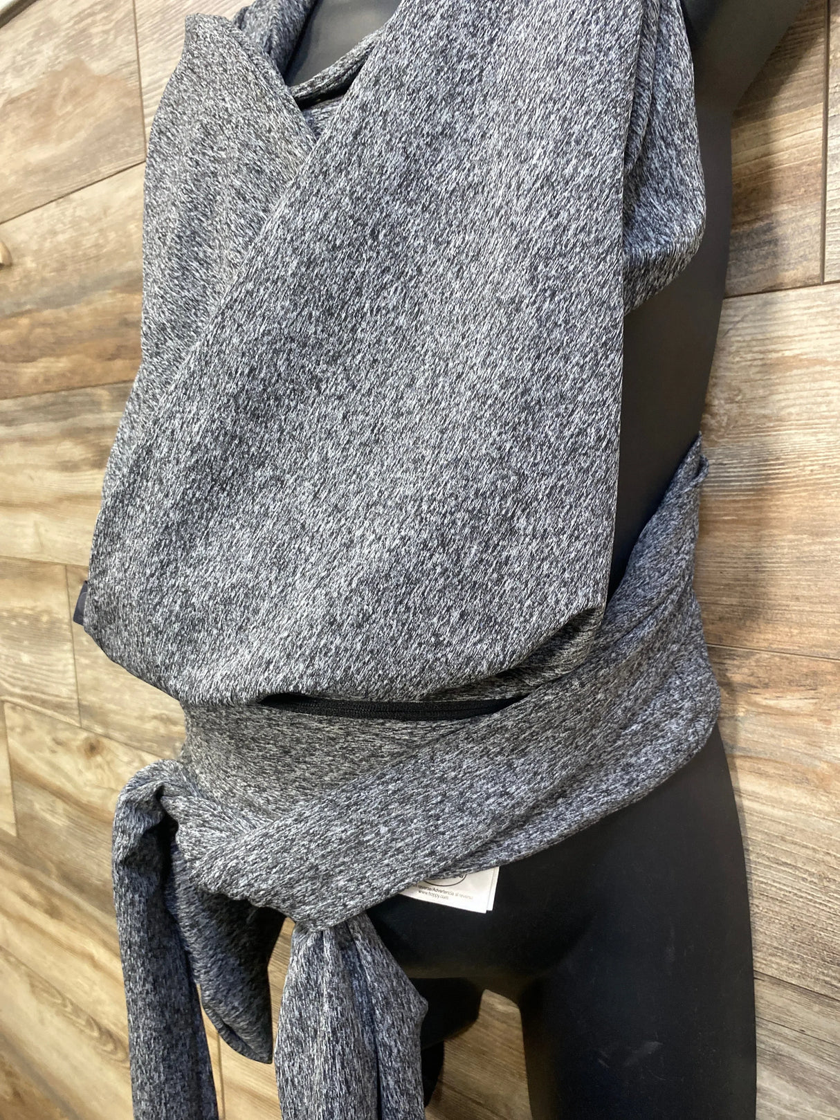 Front view of Boppy ComfyFit Hybrid baby carrier showing grey marled crossover wrap tied at the waist on a black mannequin