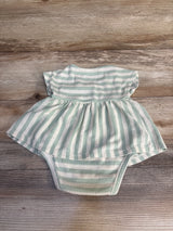 Mint green and white striped baby romper with ruffled skirt, laid on wood floor