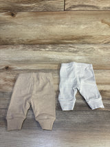 Flat lay of two newborn knit pants (solid beige and beige-striped) showcasing elastic waist and cuffed ankles on wood background