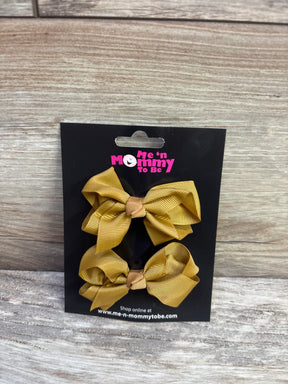 Front view of 2-pack caramel grosgrain hair bows clipped to a black Me n Mommy To Be card on a light wood background